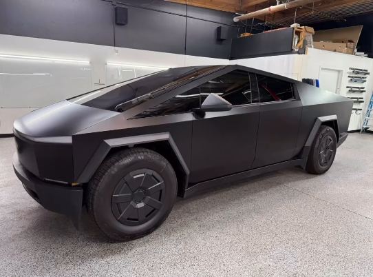 A black Tesla Cybertruck is parked in a garage.