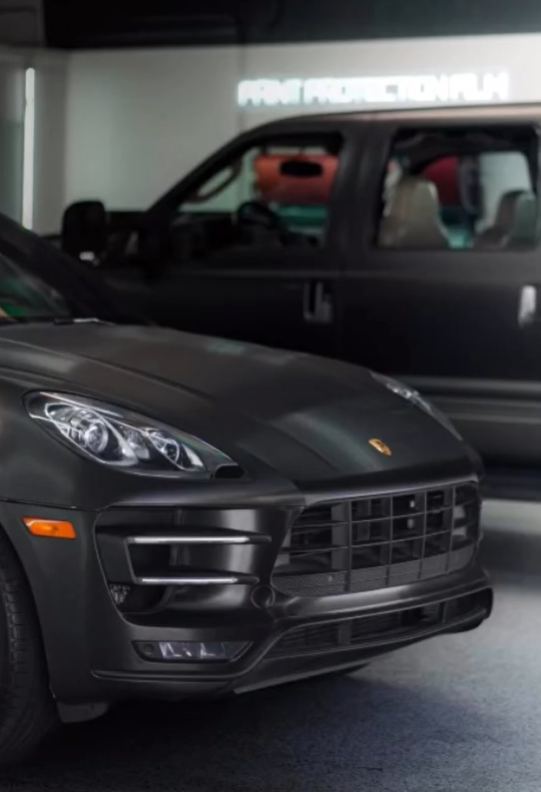 A black Porsche is parked next to a black truck