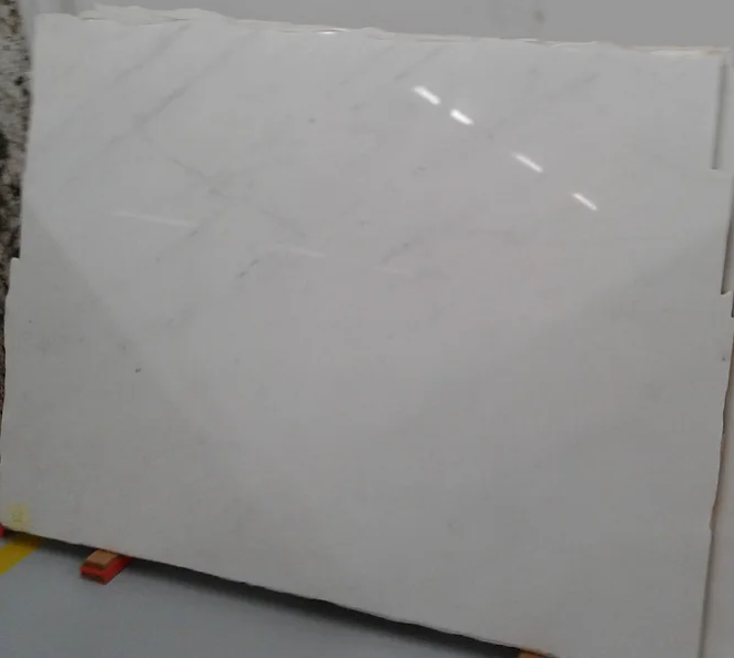 A large white marble slab is sitting on top of a cement floor.