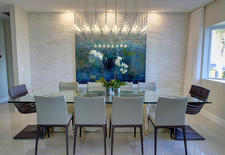A dining room with a glass table and chairs and a painting on the wall.