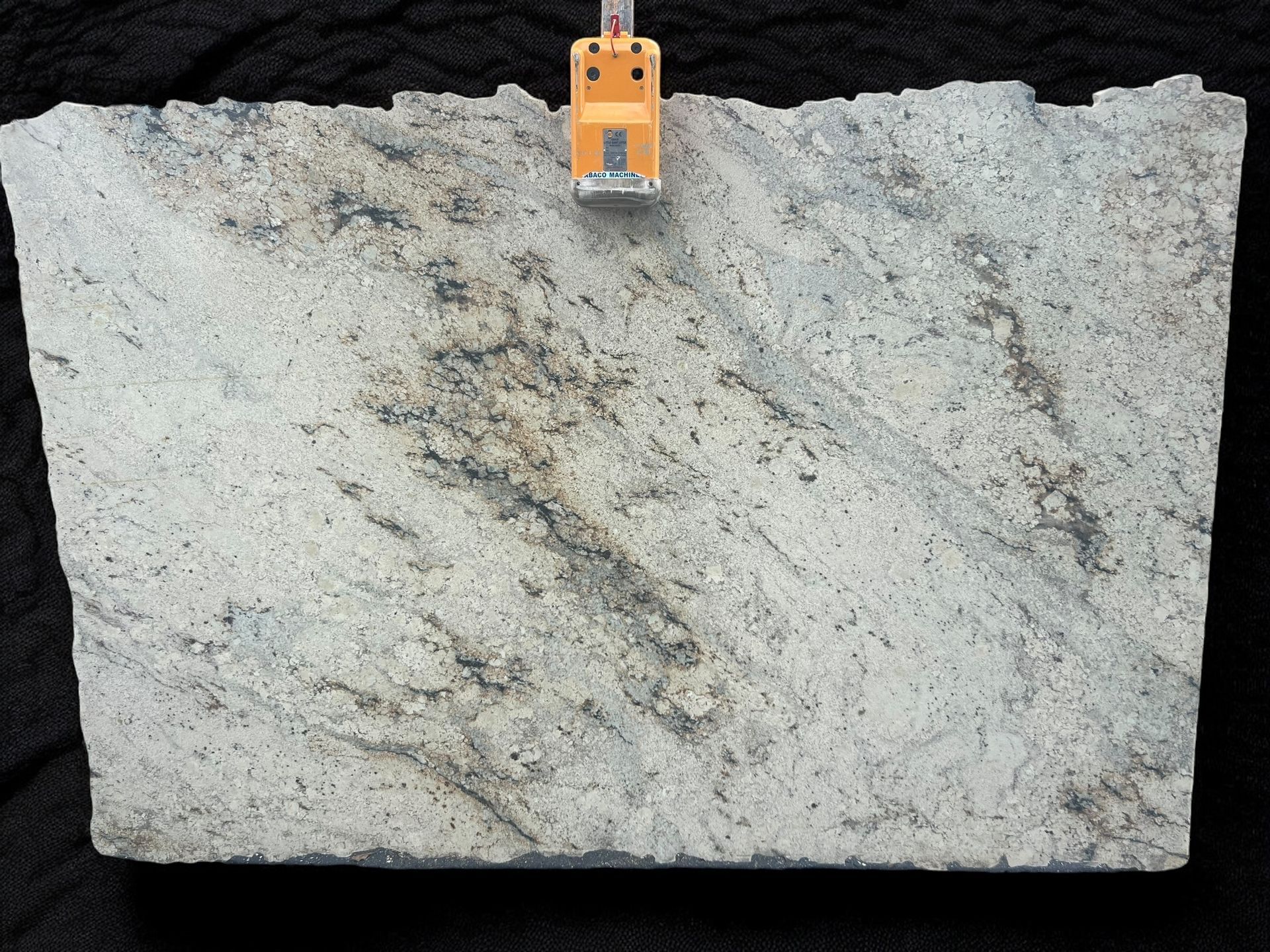 A piece of white granite is hanging on a yellow hook.