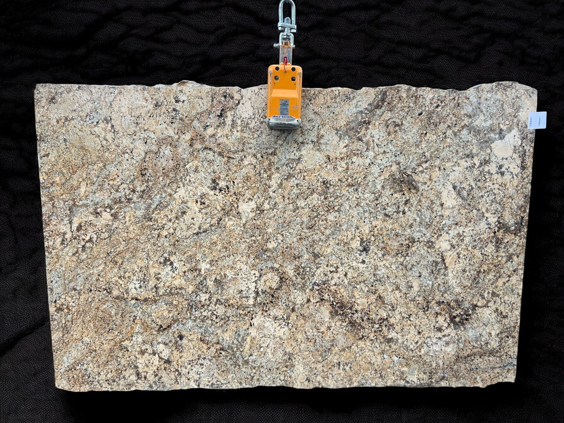 A piece of granite is hanging from a crane on a black background