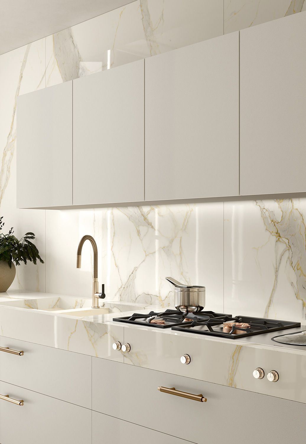 Modern kitchen with white cabinets, marble backsplash and countertops, gas stove, and gold fixtures.