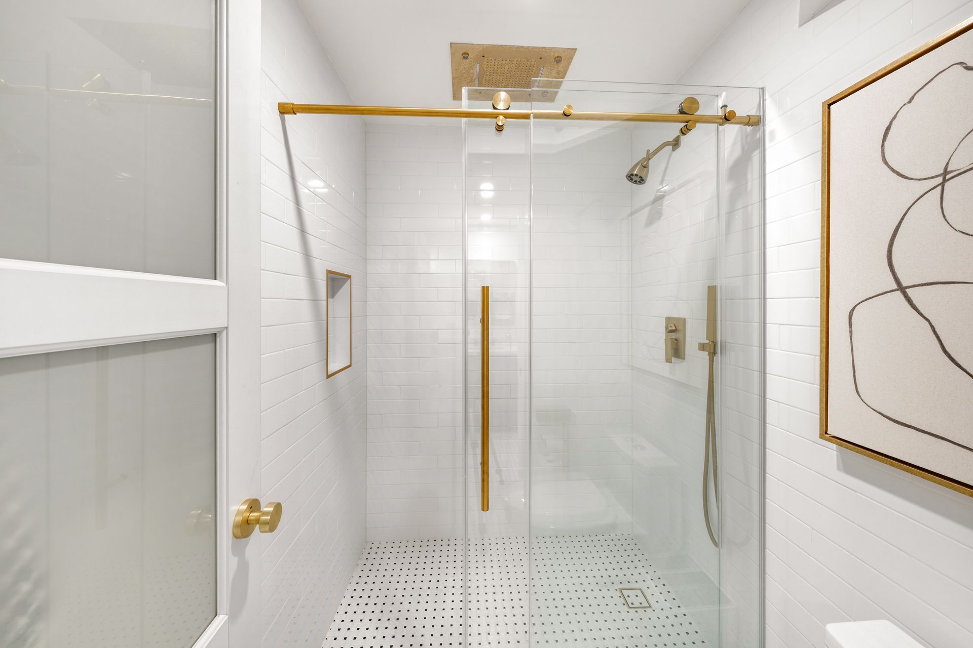 A bathroom with a sliding glass shower door and a picture on the wall.