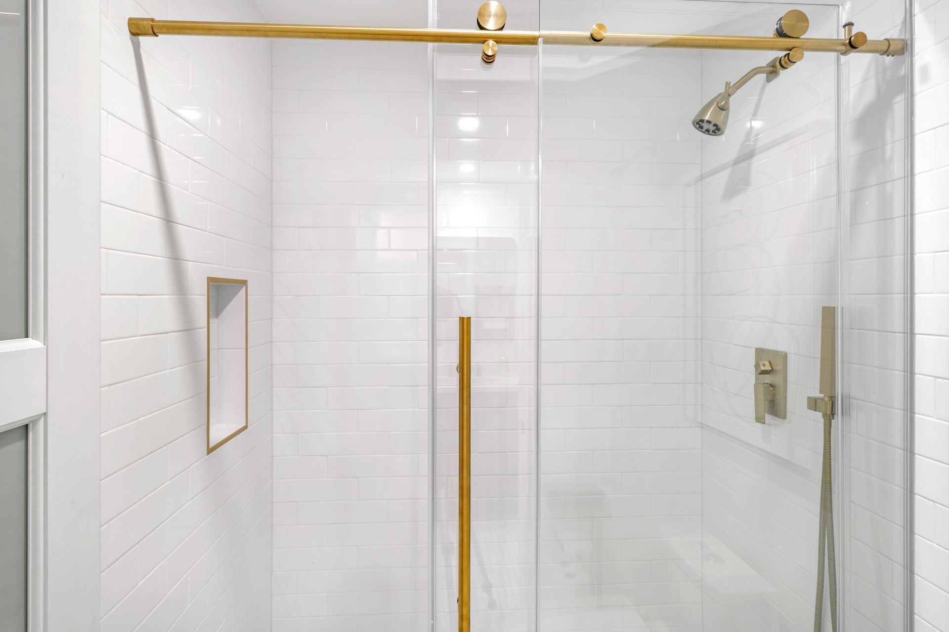 A bathroom with white tiles and a sliding glass shower door.