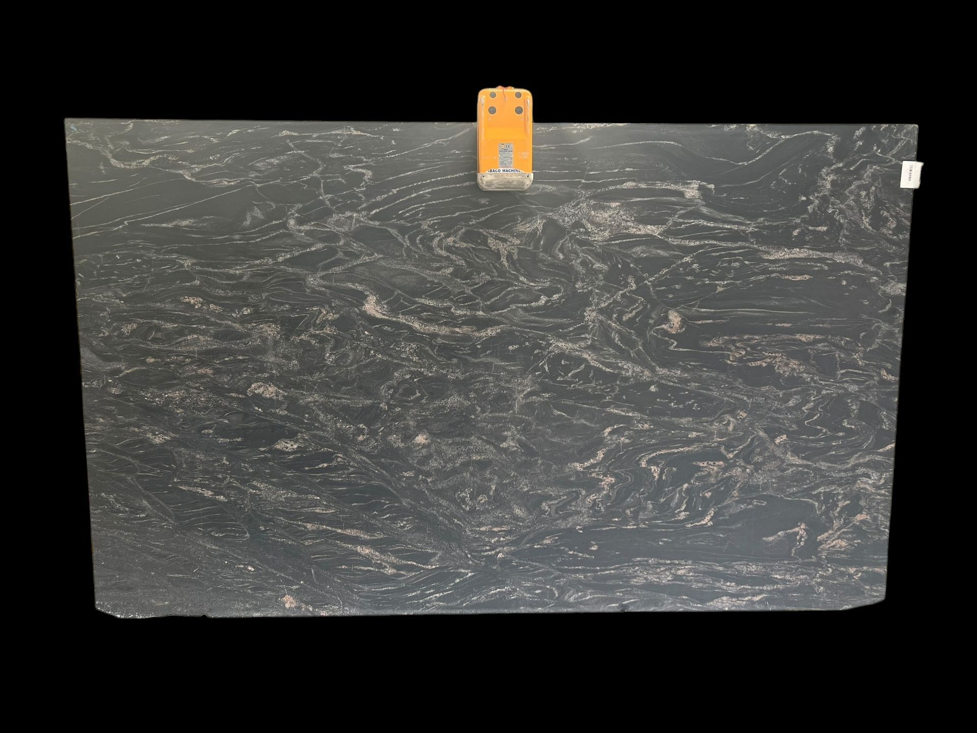 A black granite slab is hanging on a hanger on a black background.