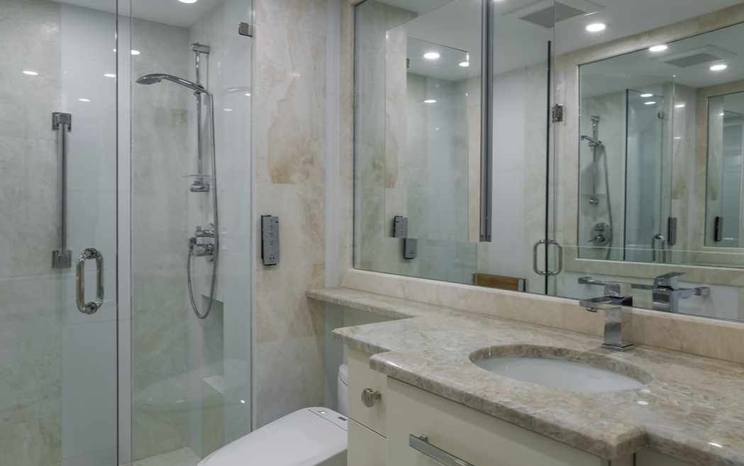 A bathroom with a toilet , sink , shower and mirror.