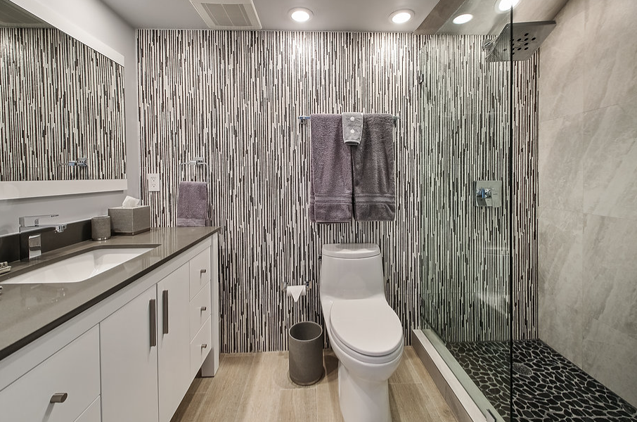 A bathroom with a toilet , sink , mirror and walk in shower.