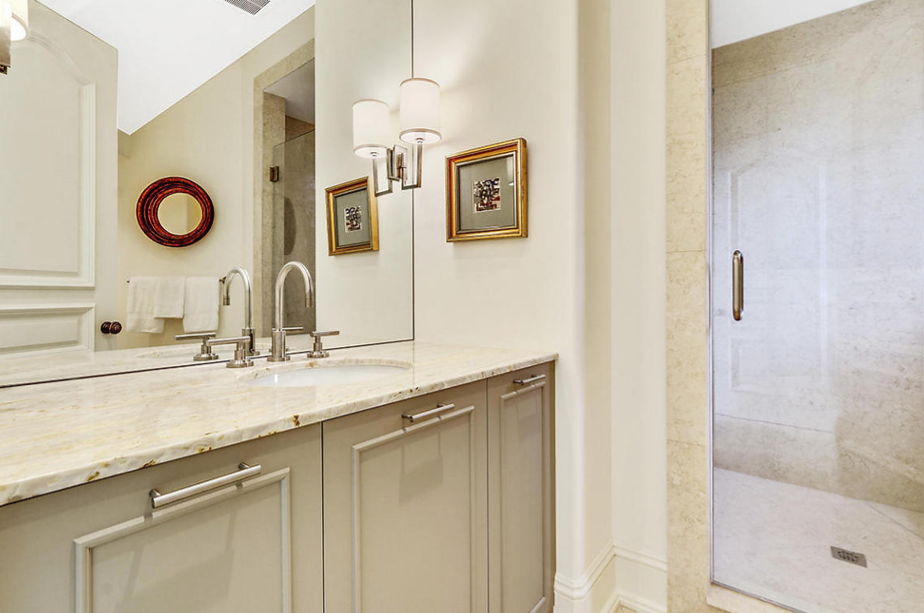 A bathroom with a sink , mirror and walk in shower.