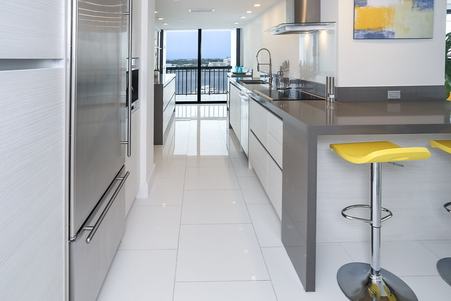 A kitchen with stools and a stainless steel refrigerator