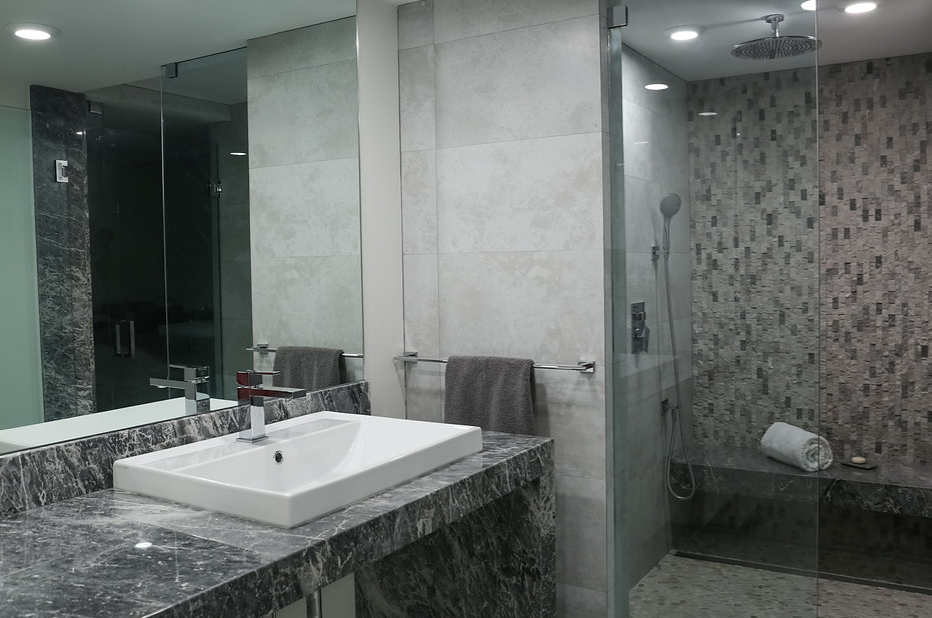 A bathroom with a sink , mirror and walk in shower.