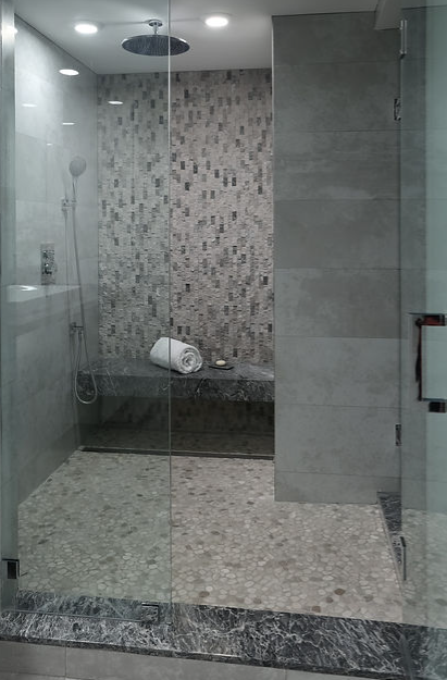 A bathroom with a walk in shower and a bench.
