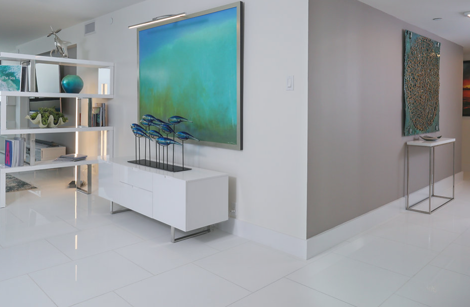 A living room with a blue painting on the wall and a white dresser.