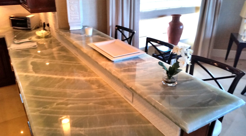 A kitchen with a marble counter top and chairs