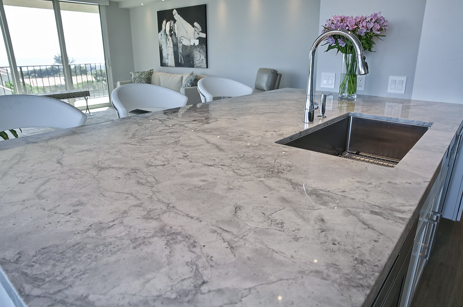 A kitchen with a marble counter top and a sink