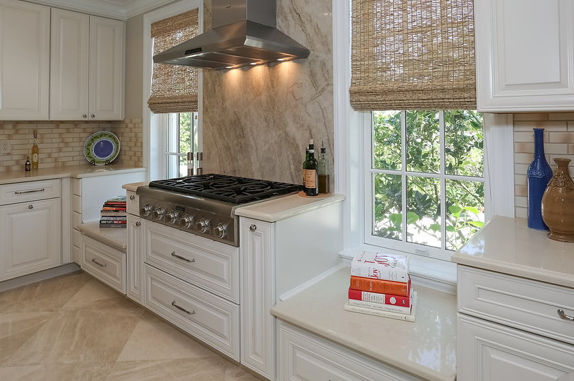 A kitchen with white cabinets and a stove top oven.