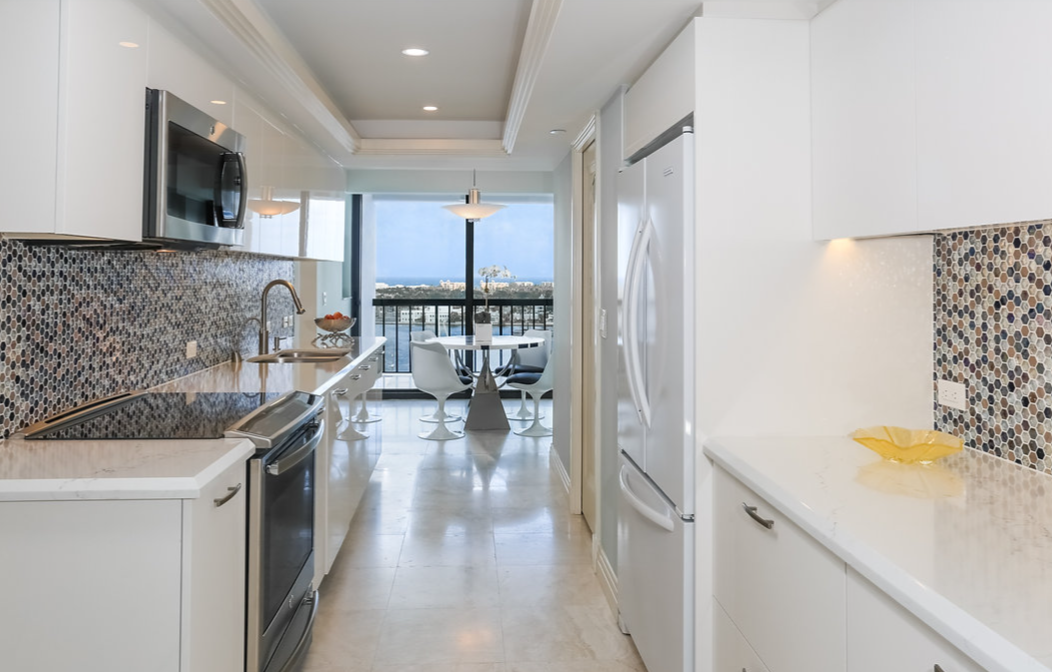 A kitchen with white cabinets , stainless steel appliances , a refrigerator and a microwave.