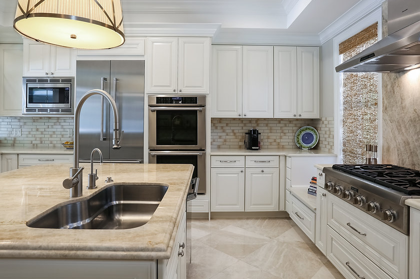 A kitchen with white cabinets , stainless steel appliances , a sink and a stove.