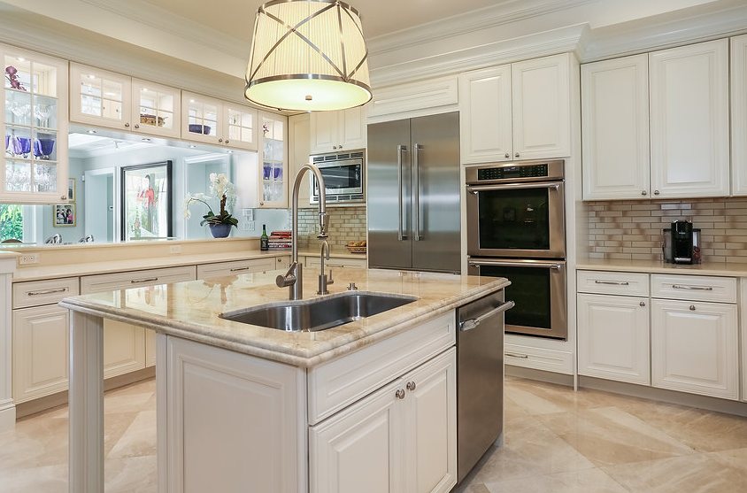 A kitchen with white cabinets , granite counter tops , stainless steel appliances and a large island.