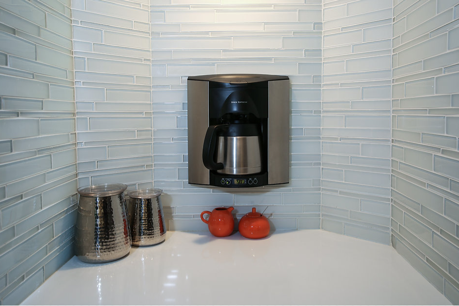 A coffee maker is hanging on the wall above a counter.