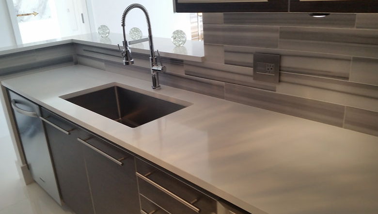 A kitchen with a sink , dishwasher , and cabinets.