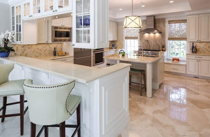 A kitchen with white cabinets , granite counter tops , and stools.