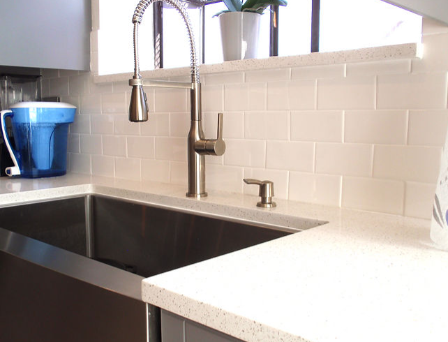 A kitchen sink with a faucet and a pitcher on the counter