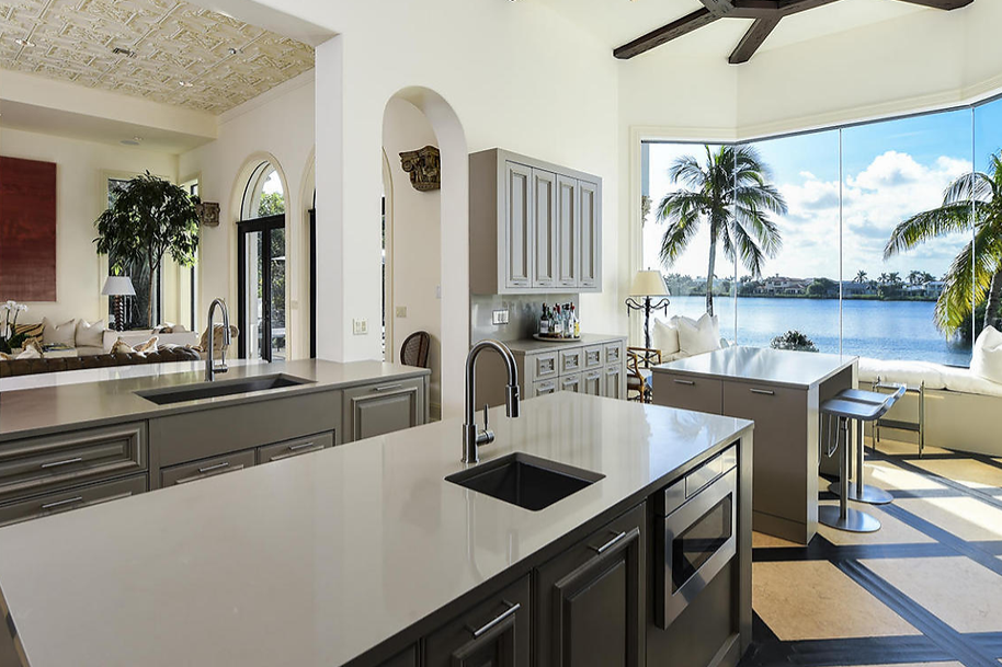 A kitchen in a house with a view of the ocean and palm trees.