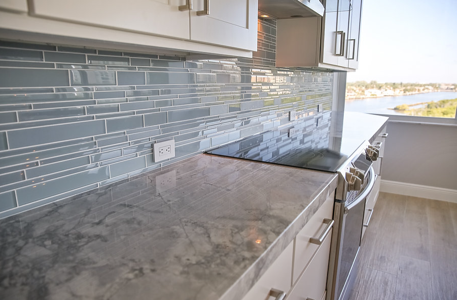 A kitchen with a stove top oven and a marble counter top.