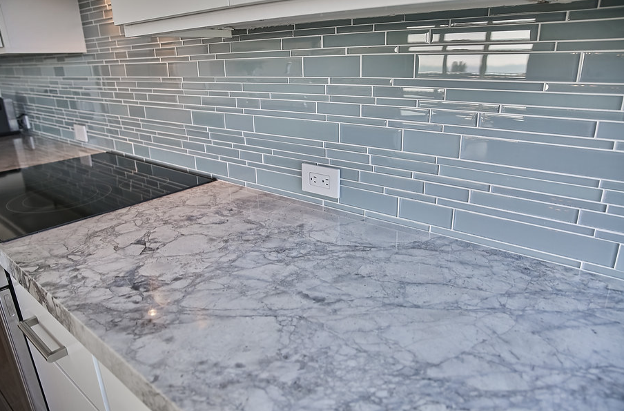 A kitchen counter with a stove top oven and a marble counter top.
