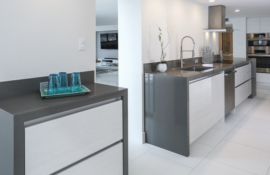 A kitchen with white cabinets and a black counter top