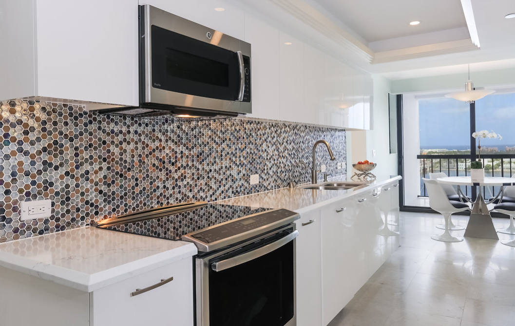 A kitchen with white cabinets , stainless steel appliances , a microwave and a stove.