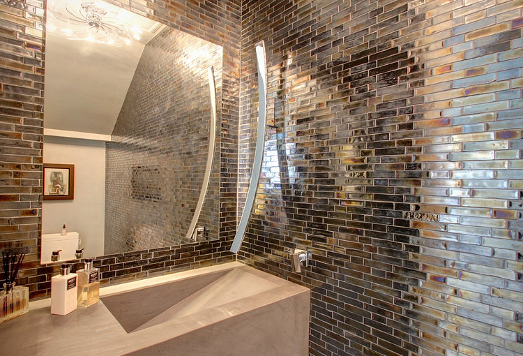 A bathroom with a sink , mirror and brick wall.