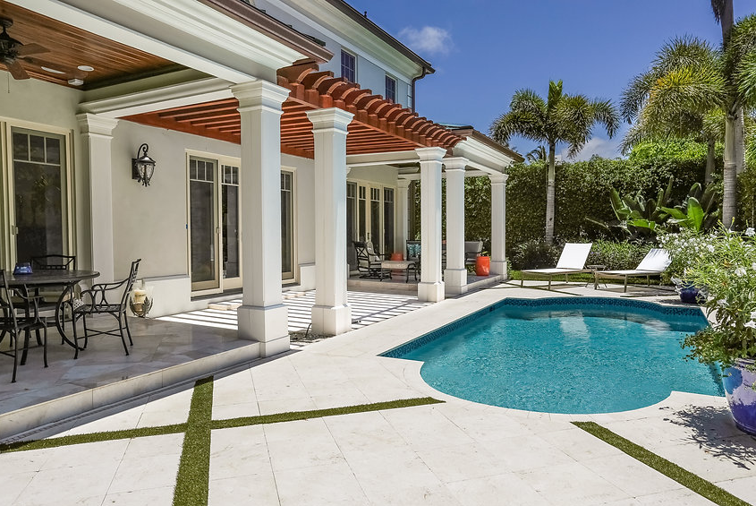 There is a large swimming pool in the backyard of a house.