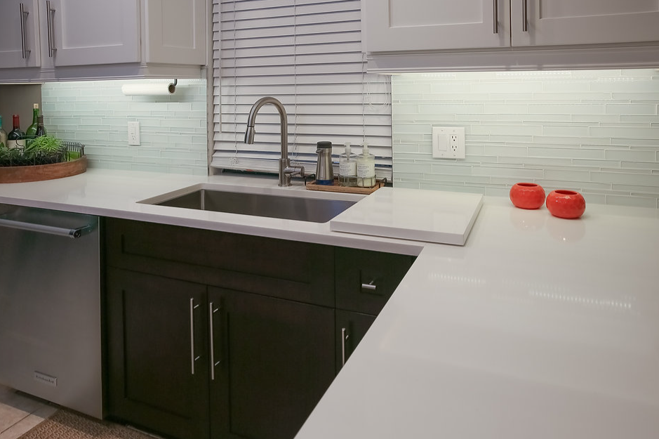 A kitchen with a sink , cabinets , and a dishwasher.