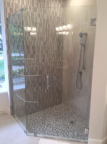 A bathroom with a walk in shower with a glass door.