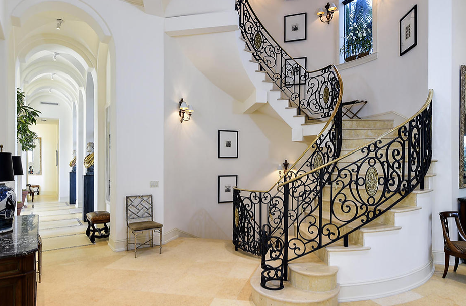 A staircase with a wrought iron railing in a hallway