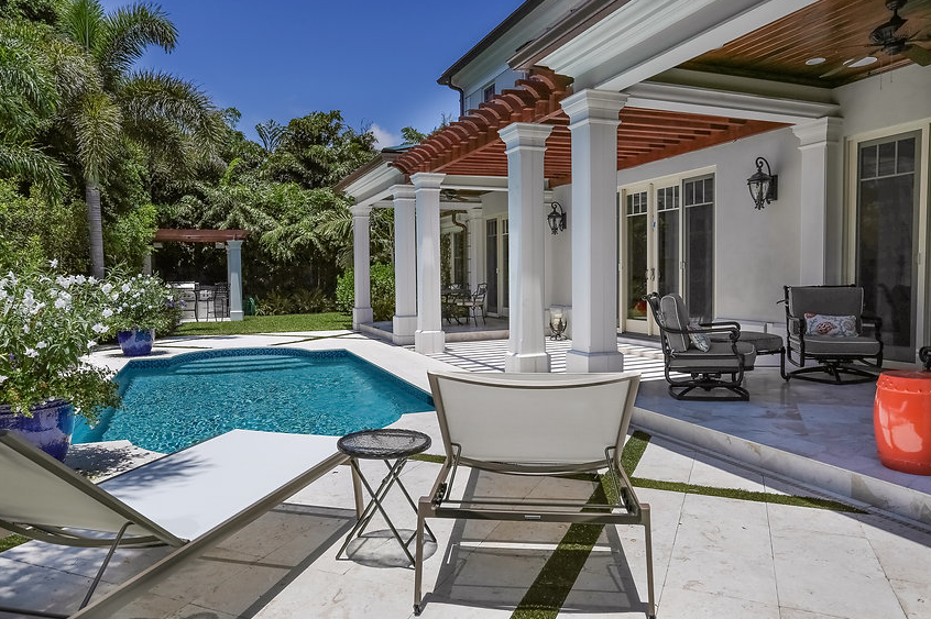 There is a large swimming pool in the backyard of a house.