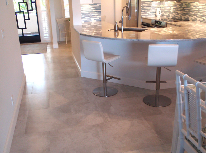 A kitchen with a marble counter top and white chairs