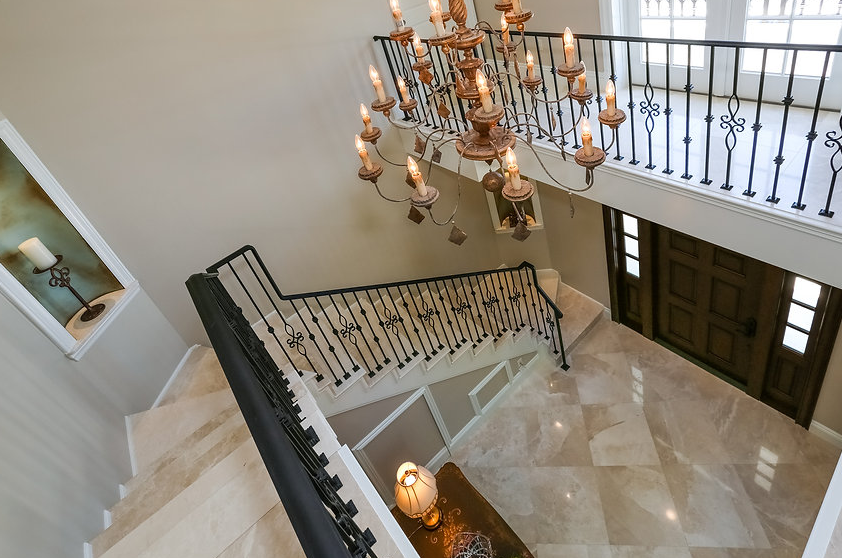 An aerial view of a staircase with a chandelier hanging from the ceiling