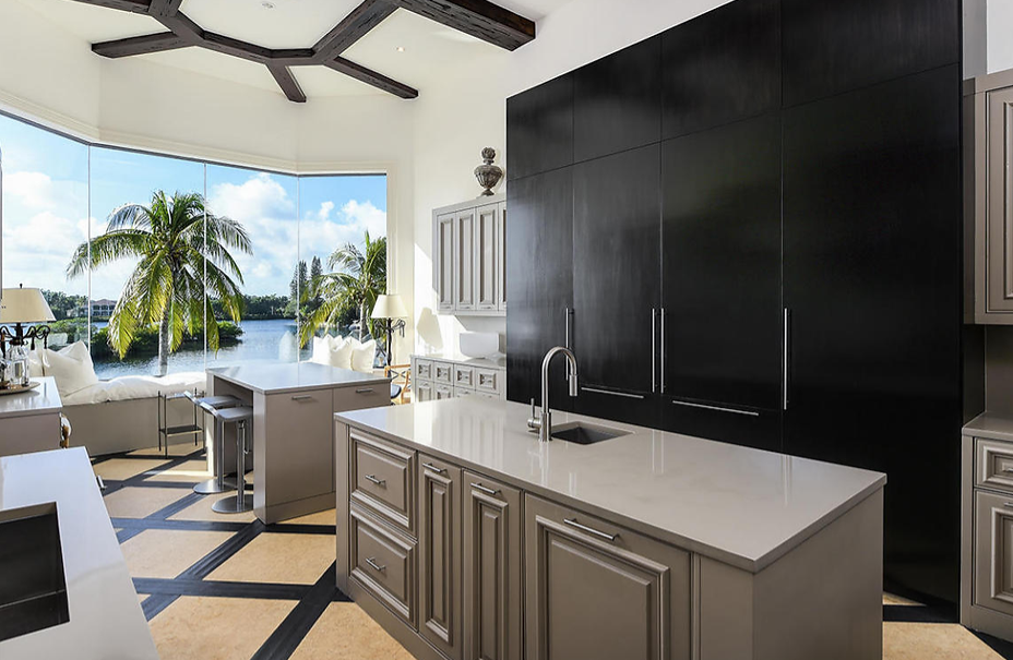 A kitchen with black cabinets and a large island with a view of a lake.