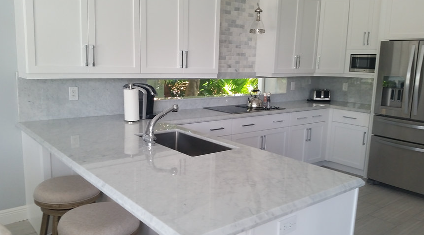 A kitchen with white cabinets , stainless steel appliances , a sink , and a refrigerator.