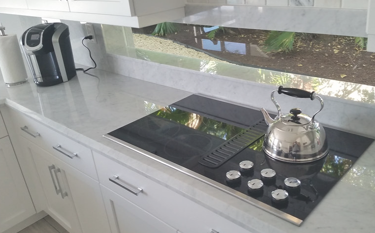 A kitchen with a stove top oven and a tea kettle on it.