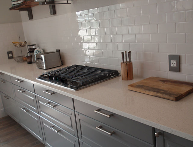 A kitchen with a stove top oven and a cutting board on the counter.