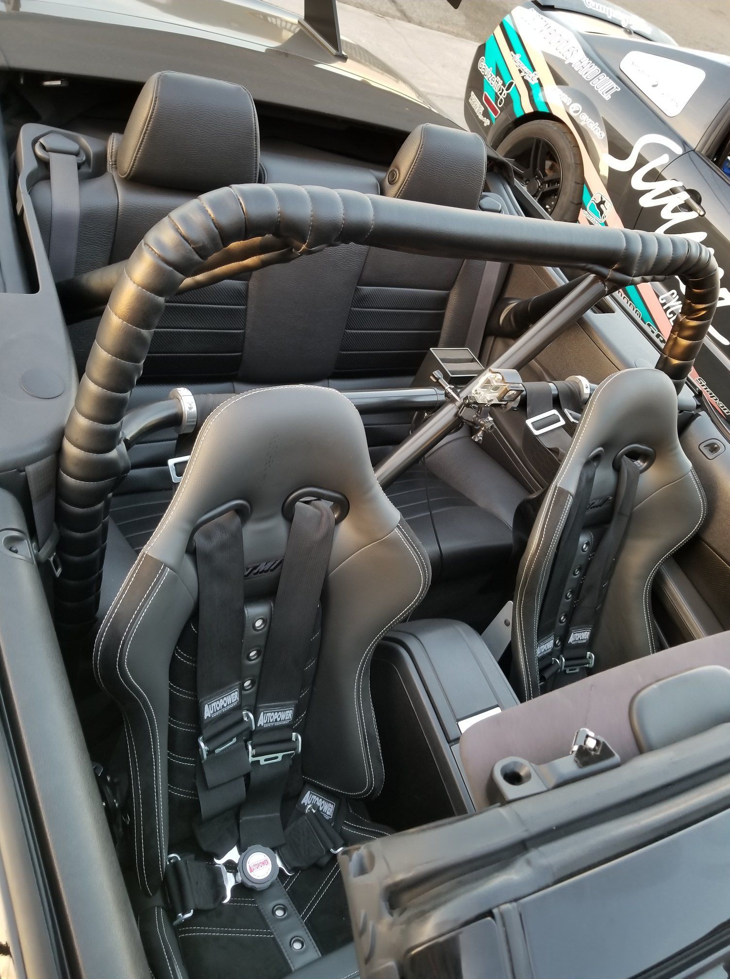 Black convertible car interior with racing seats and roll bar.