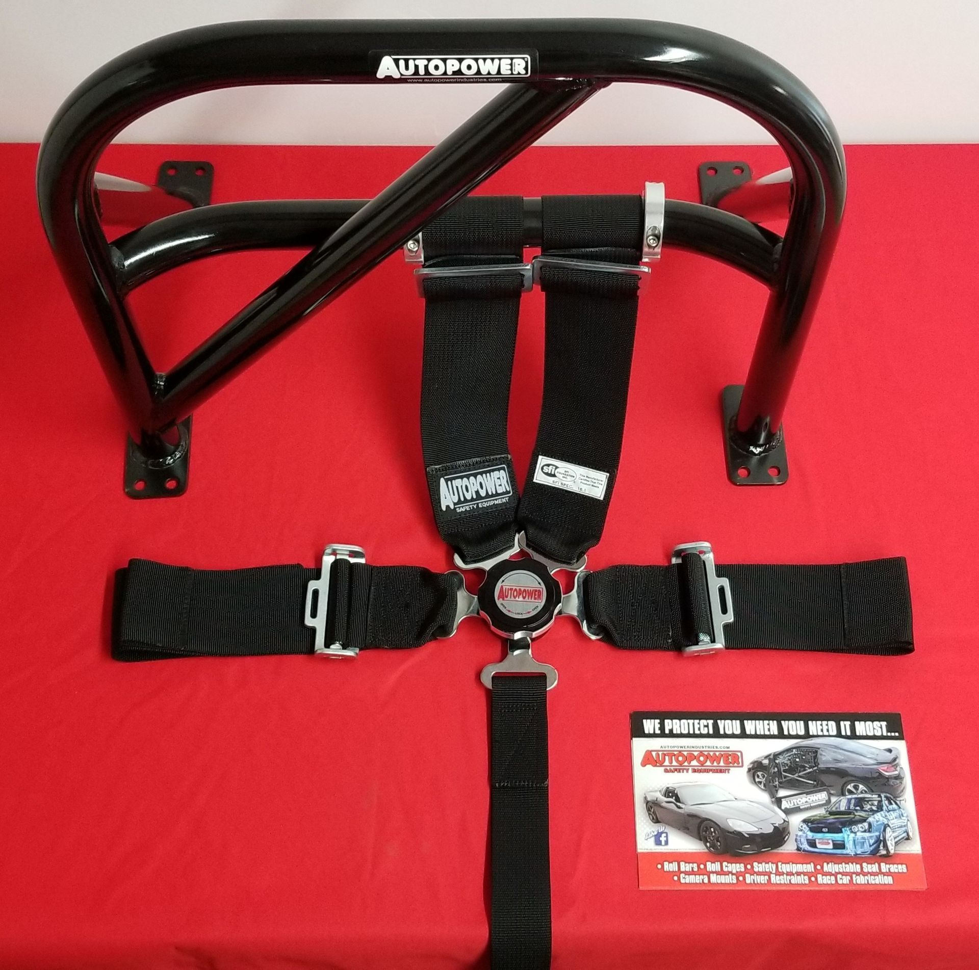 Black roll cage and racing safety belts on a red surface, with a promotional card.