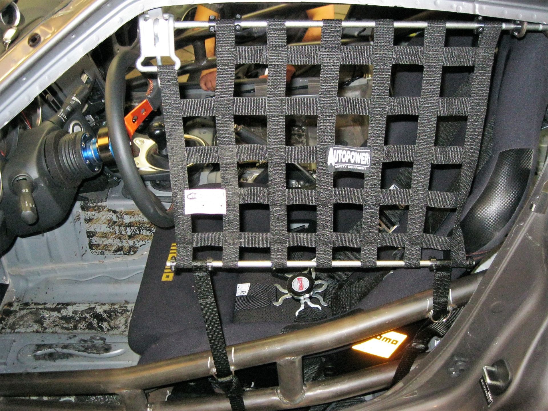 Black safety window net installed in a car, protecting the driver from side impact during racing.