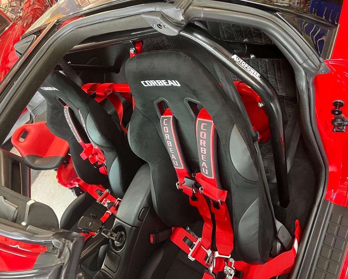 Red car interior with racing seats and safety harnesses.