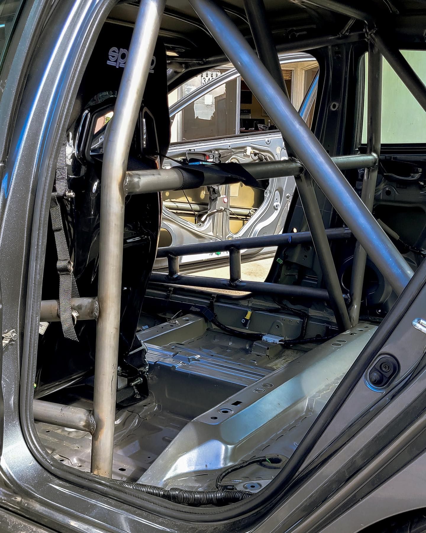 Interior of a race car, showing roll cage and driver's seat. Gray metal and black seat.
