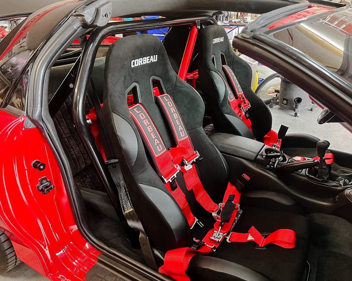 Red sports car interior with black racing seats and red harnesses.